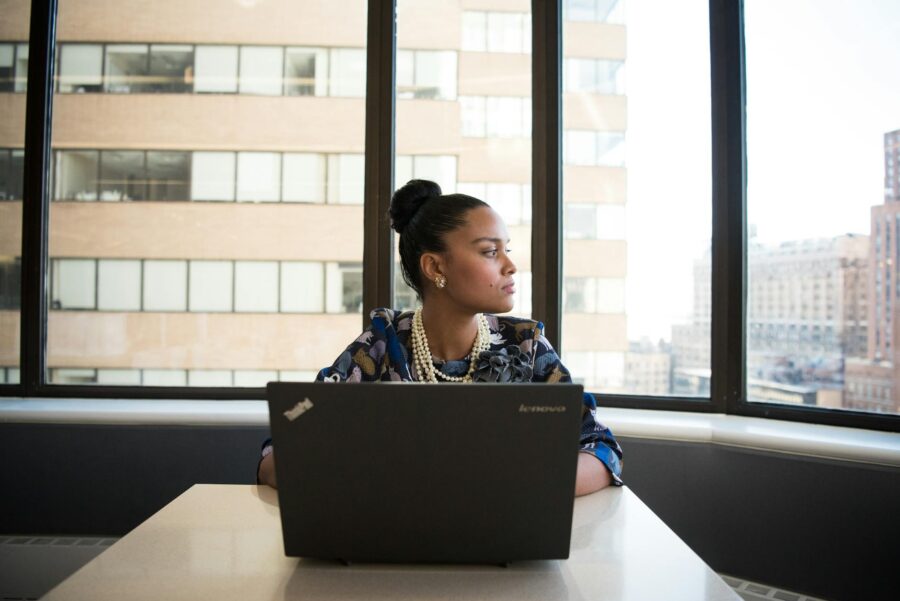 woman sits in front of black laptop computer